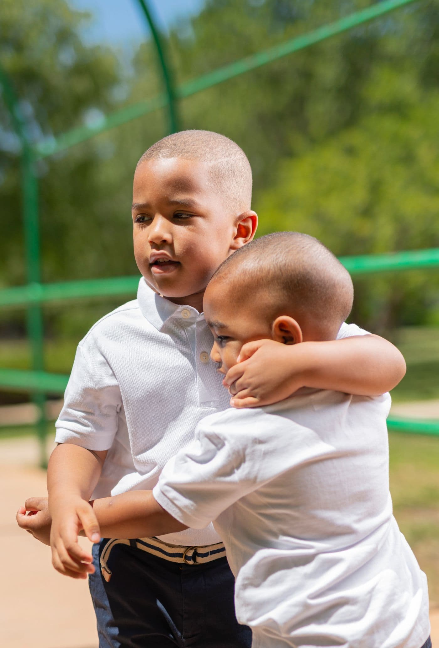 Two young brothers embracing at a neighborhood playground